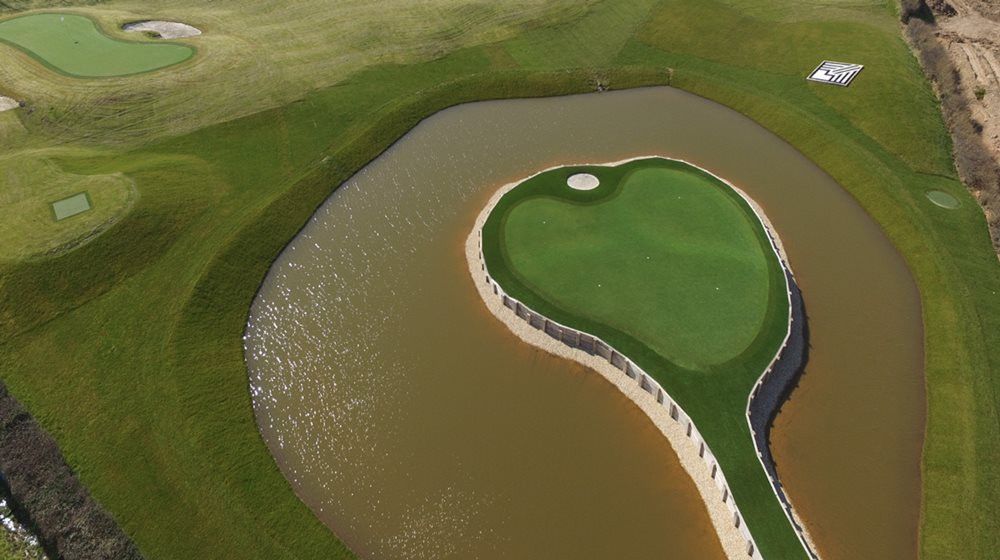 Vancouver Aerial view of a vibrant green synthetic grass island in a natural pond on a golf course